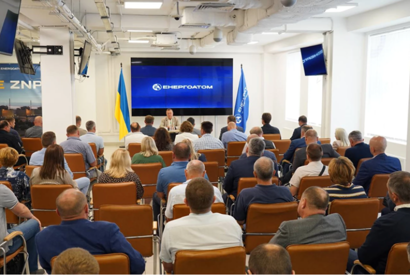 Засідання працівників «Енергоатом» у конференц-залі, люди сидять у рядах перед великим екраном із логотипом.
