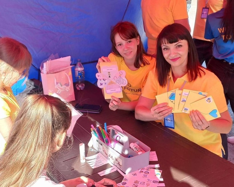 Студентки коледжу з дітьми створюють листівки для військових у межах патріотичної ініціативи під час літніх канікул.