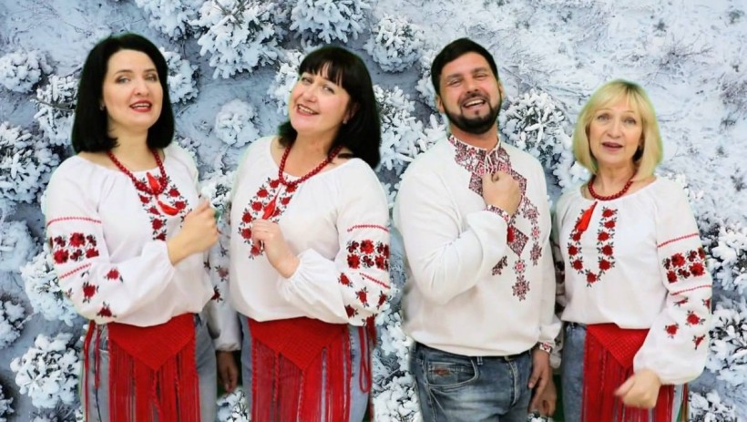 Співаки у національних костюмах на фоні засніжених ялинок