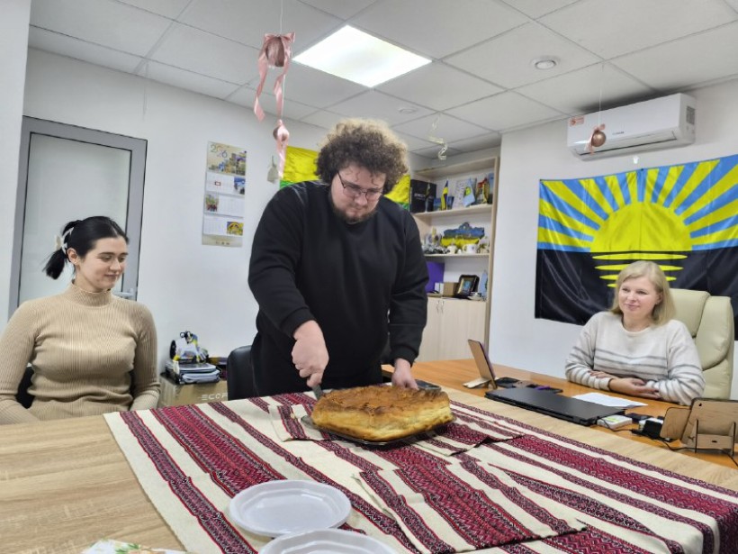 Чоловік розрізає василопіту - традиційний новорічний обряд надазовських греків