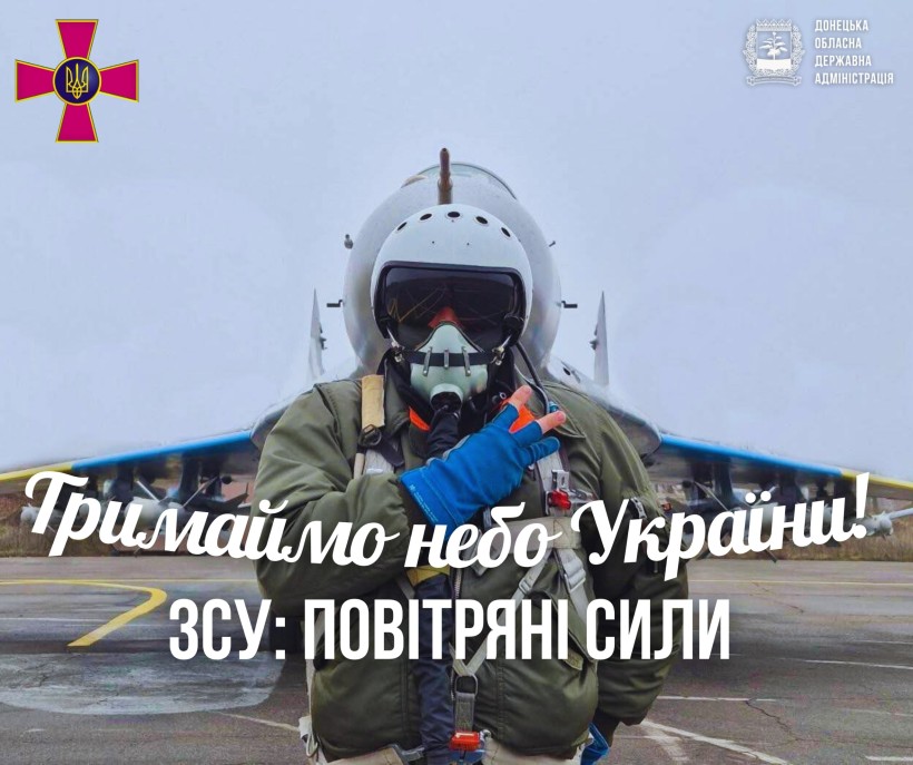 Пілот у повному польотному спорядженні впевнено стоїть перед винищувачем на злітно-посадковій смузі. Текст накладено на зображення, передаючи сильне патріотичне послання.