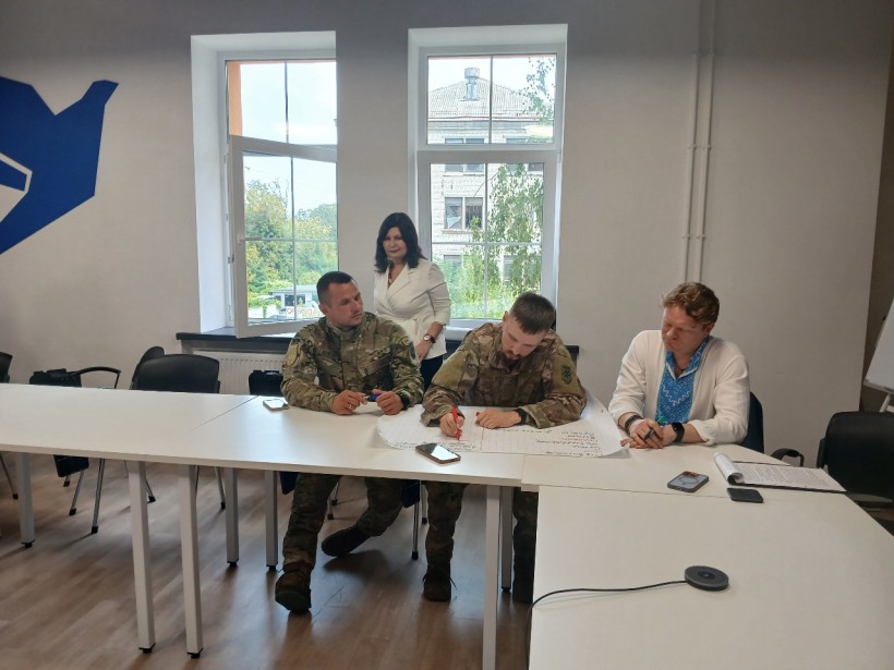 Учасники уроку «Донеччина – форпост незламної країни» за круглим столом. На передньому плані - військові.