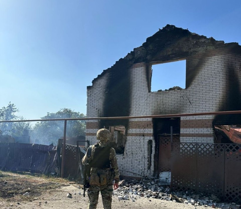 Правоохоронець стоїть біля знищеного та обгорілого після обстрілу окупантів будинку