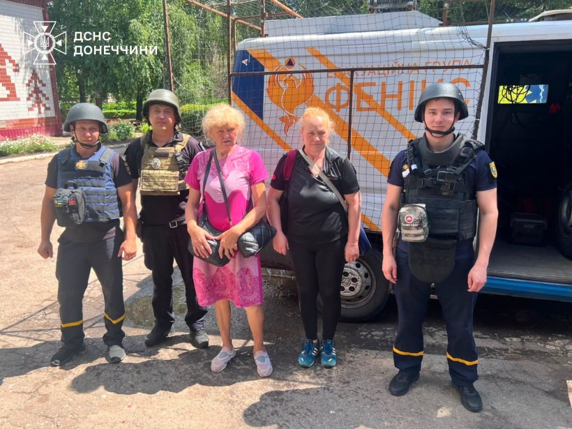 Троє мешканців Дружківки стоять з рятувальниками біля евакуаційного автомобіля