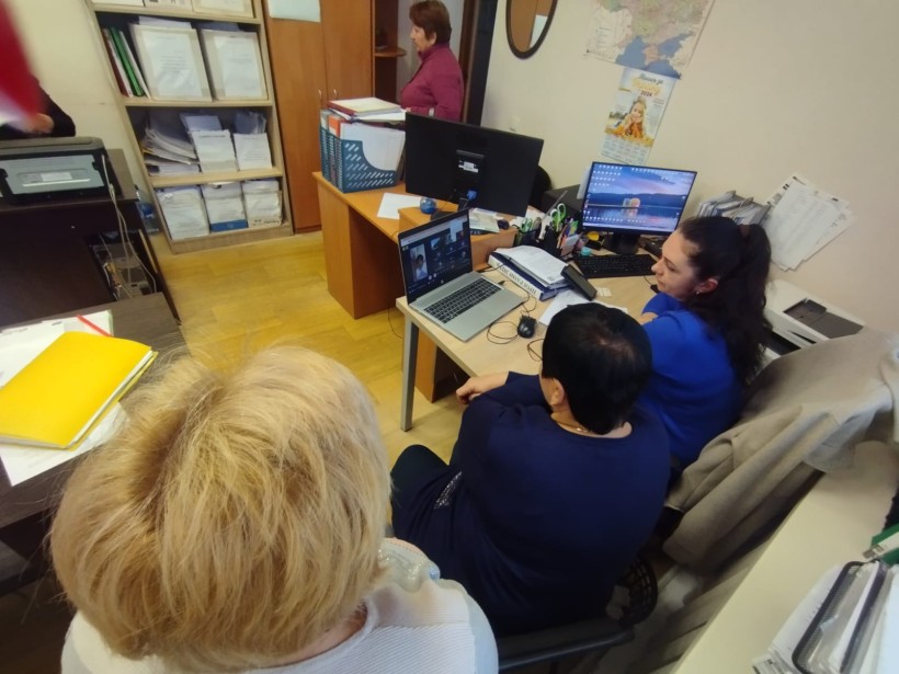 Представники військової адміністрації сидять за столом та слухають доповідача на семінарі