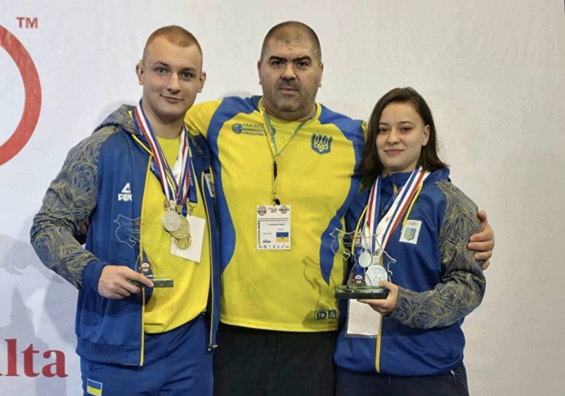 Українські спортсмени разом з тренером тримають нагороди