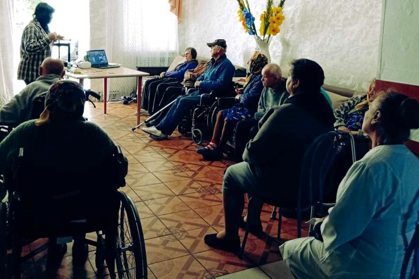Група людей похилого віку слухає презентацію ведучої