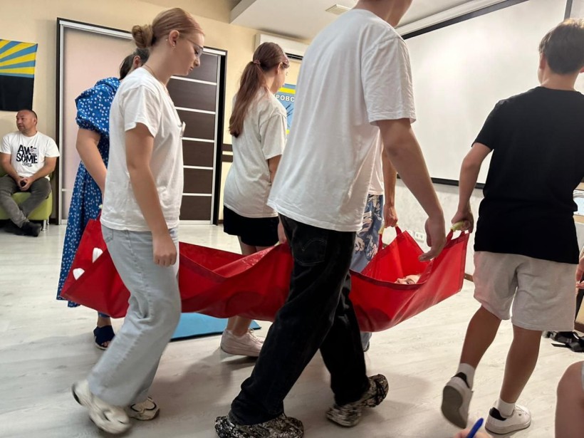 Учні тренуються транспортувати постраждалого на м`яких ношах.