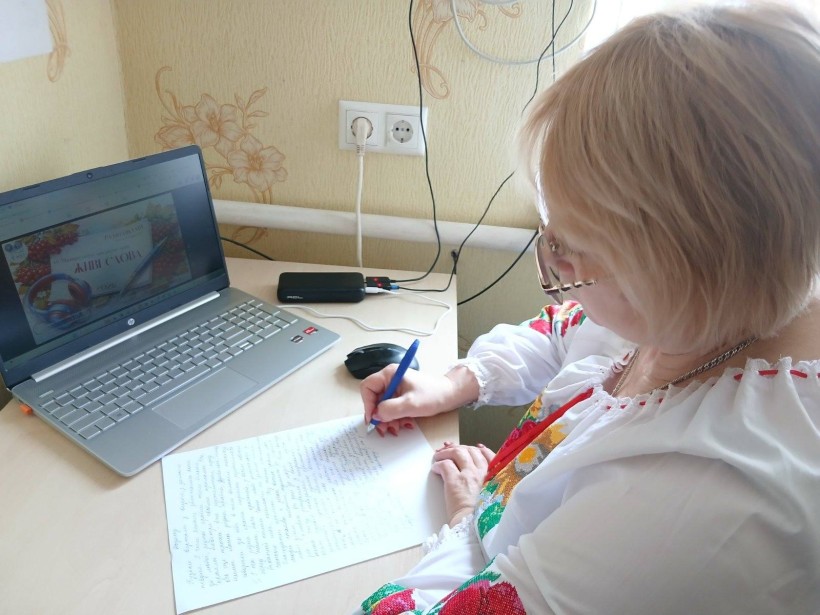 Учасник акції пише диктант перед екраном ноутбука