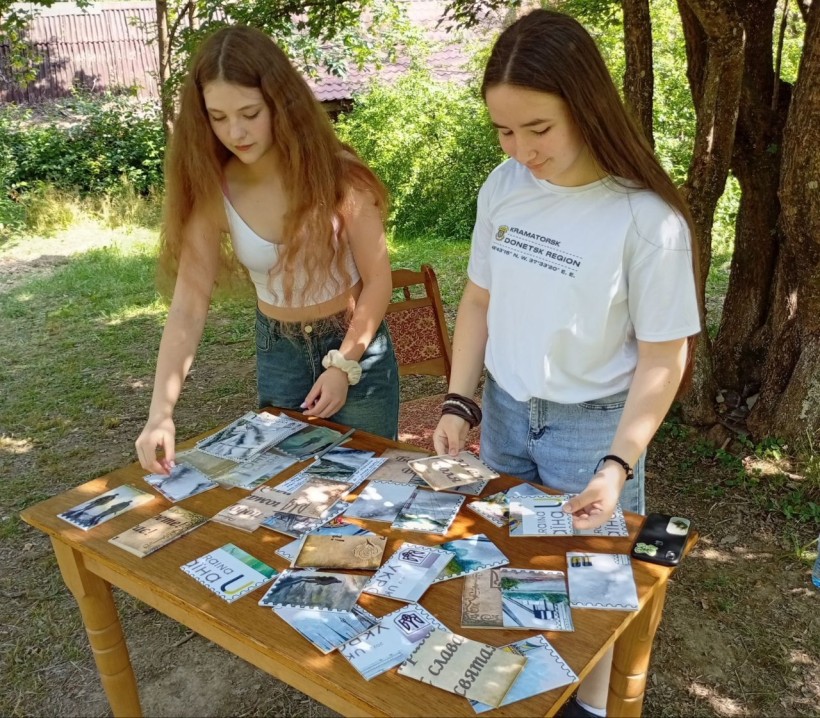 Двоє дівчат стоять біля столу з розкладеними на ньому фото