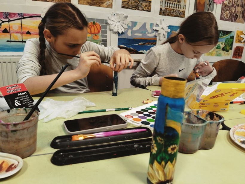 Солотвинська громада організувала майстер-клас з розпису гільз. Дівчата сидять за партою та майструють.