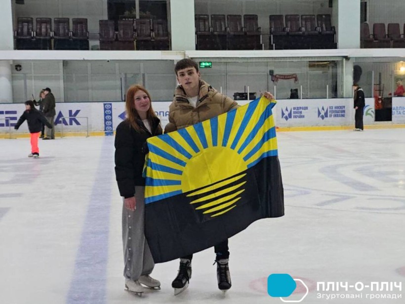 Молоді люди стоять на льоду у  льодовій арені та тримають прапор Донеччини.