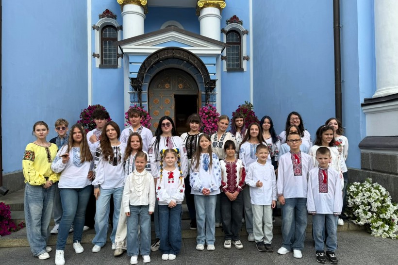 Спільне фото дитячого хору у вишиванках на тлі входу до храму.