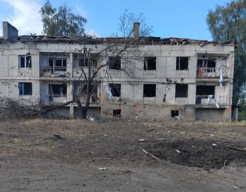 Багатоповерхівка, зруйнована обстрілом окупантів та воронка перед нею.