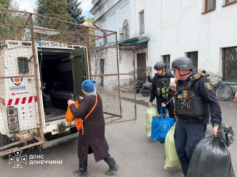 Рятувальники Донеччини допомагають жінці завантажити речі в евакомобіль