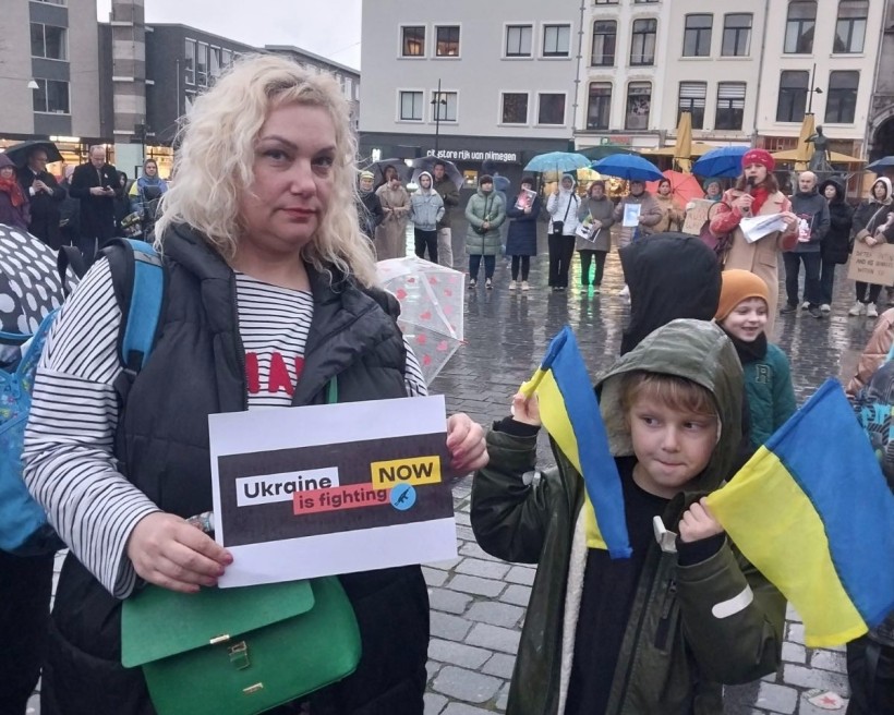 Викладачка бахмутського педагогічного фахового коледжу тримає плакат «Ukraine is fighting now» під час на мітингу на підтримку України.