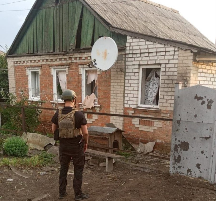 Правоохоронець стоїть біля пошкодженого окупантами будинку