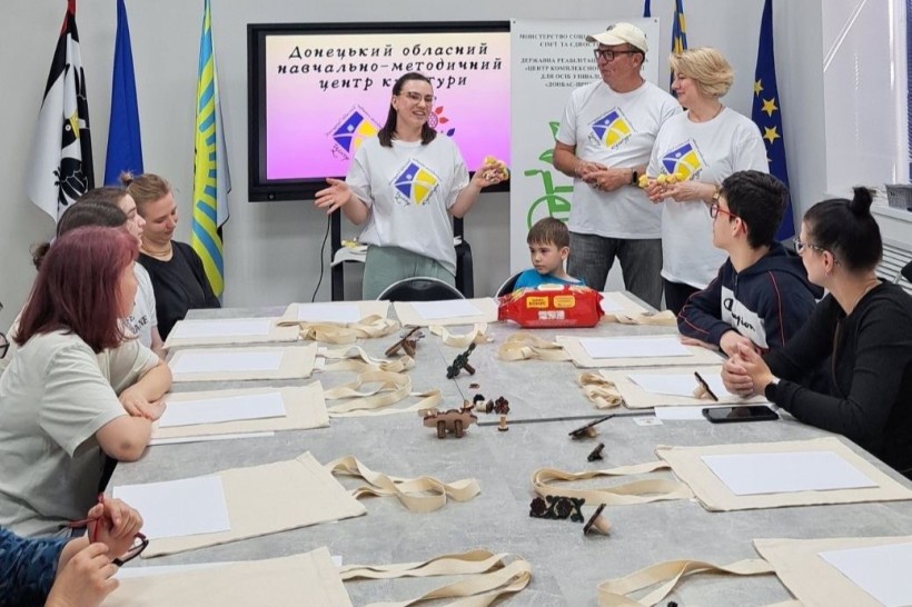 Організатори в білих футболках з логотипом презентують матеріали для майстер-класу
