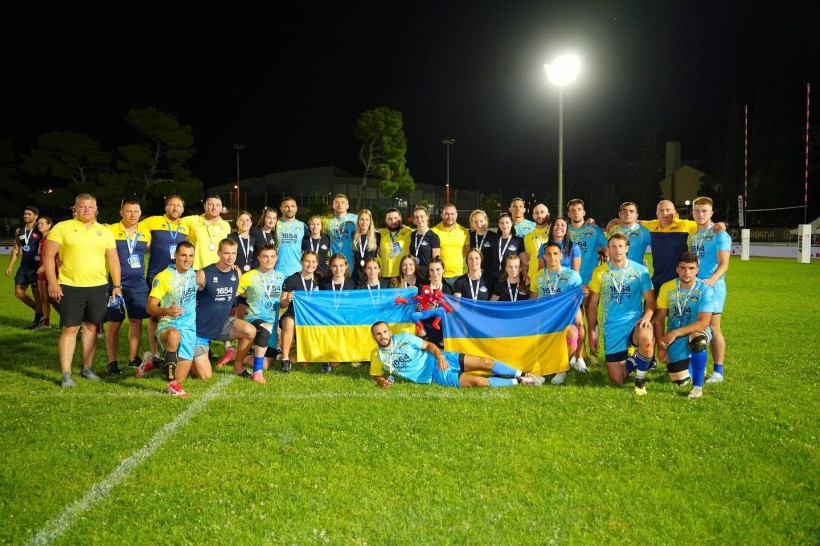 Чоловіча національна збірна України з регбі фотографується з українськими прапорами на спортивному полі в Хорватії