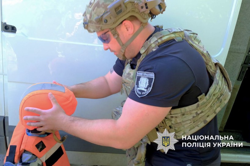 Поліцейський допомагає дитині вдягнути бронежилет