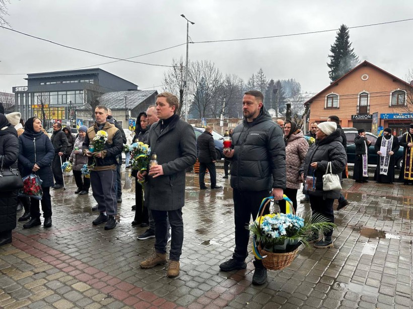 Вшанування пам'яті загиблих захисників, представники громади тримають квіти та лампадки.