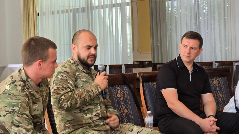 Заступник голови Донеччини Юрій Ключка та двоє чоловіків у військовій формі, сидять на стільцях. Один з них розповідає, інші уважно слухають.