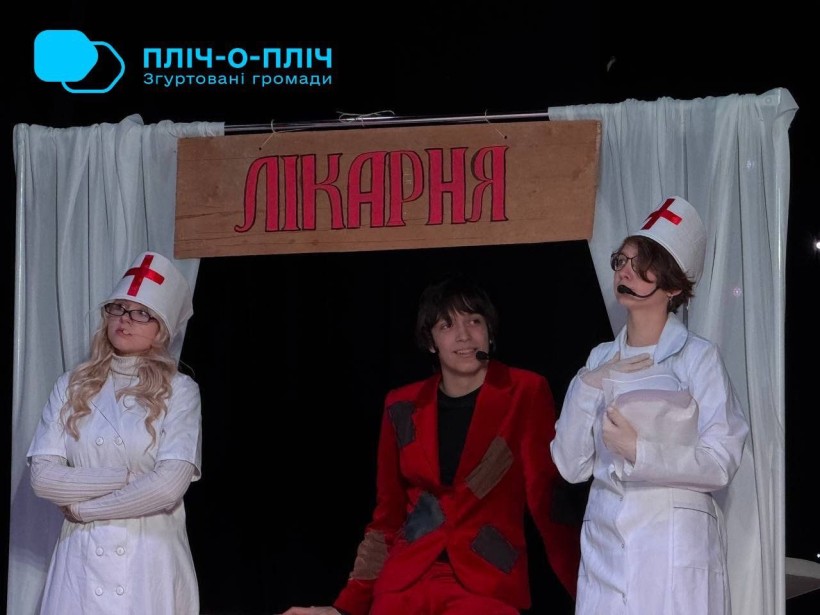 Актори на сцені. Дія у лікарні. Двоє з акторів у медичному вбранні та пацієнт.