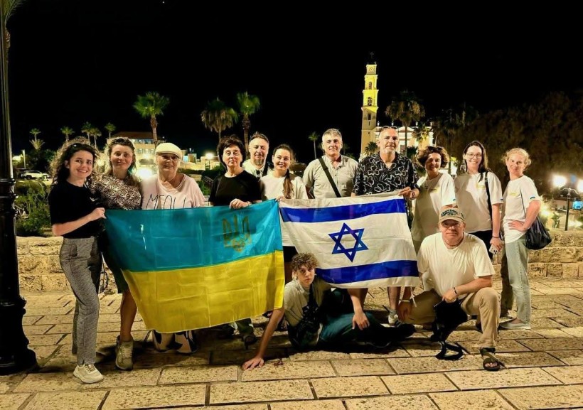 Група людей позує на вулиці, тримаючи розгорнуті прапори України та Ізраїлю.
