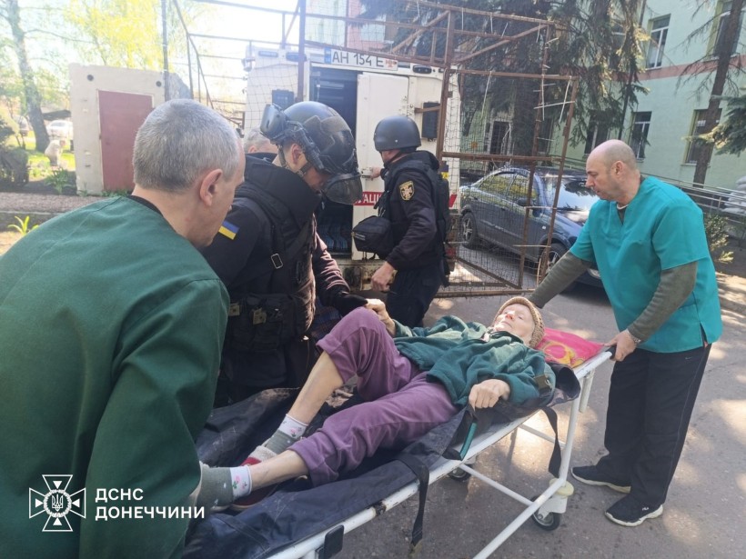 Рятувальники групи "Фенікс" разом з волонтерами допомагають лежачій жінці з евакуацією