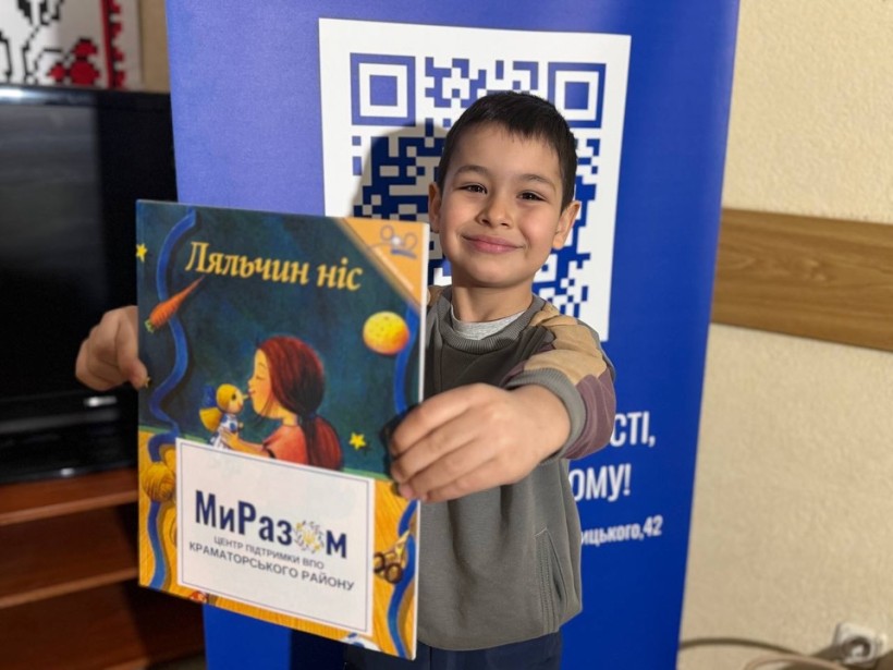 Дитина посміхаэться, тримаючи новеньку книжку