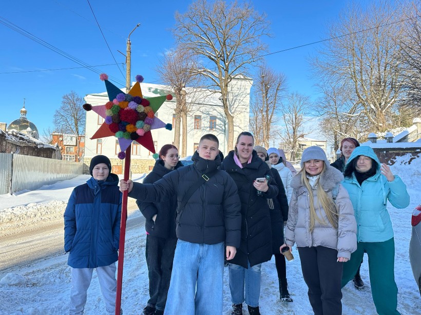 Хлопці та дівчата на вулиці. Хлопець тримає в руках палицю х різнокольоровими кульками.