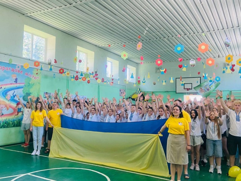 Учасники марафону «Літні мрії непереможних» із великим прапором України на завершальному патріотичному флешмобі.