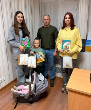 Керівник громади та діти тримають книжки та подарунки