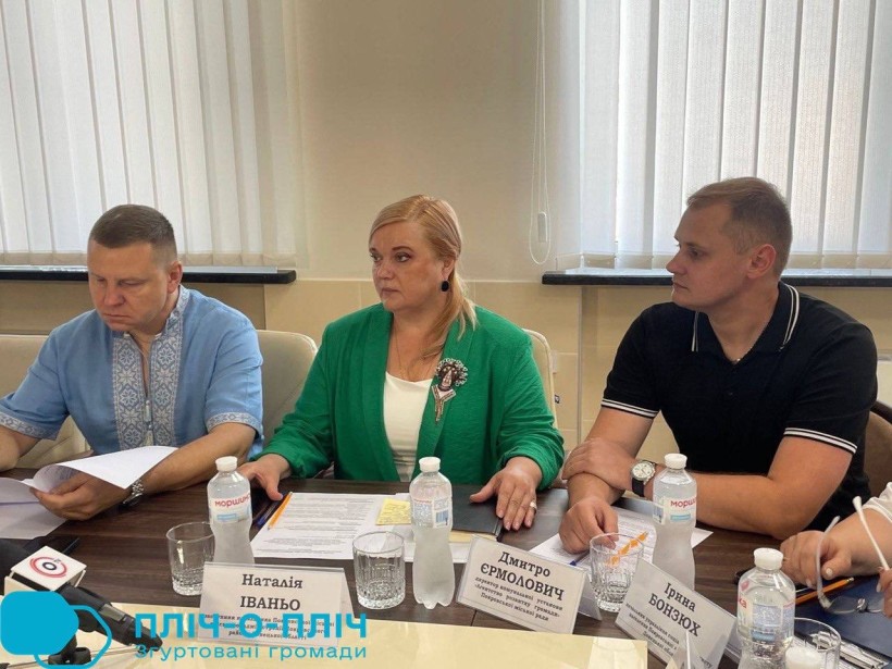Учасники делегації - представники Покровської МВА. Сидять за столом, чоловік у вишиванці уважно читає роздрукований матеріал.
