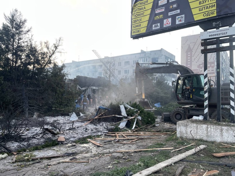 Зруйнована будівля супермаркету та екскаватор, який ліквідовує наслідки обстрілу.