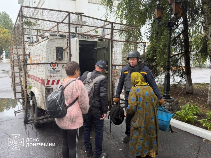 Рятувальники допомагають жінкам сісти до евакомобіля