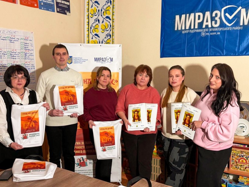 Учасники проєкту тримають сувенірну продукцію проєкту