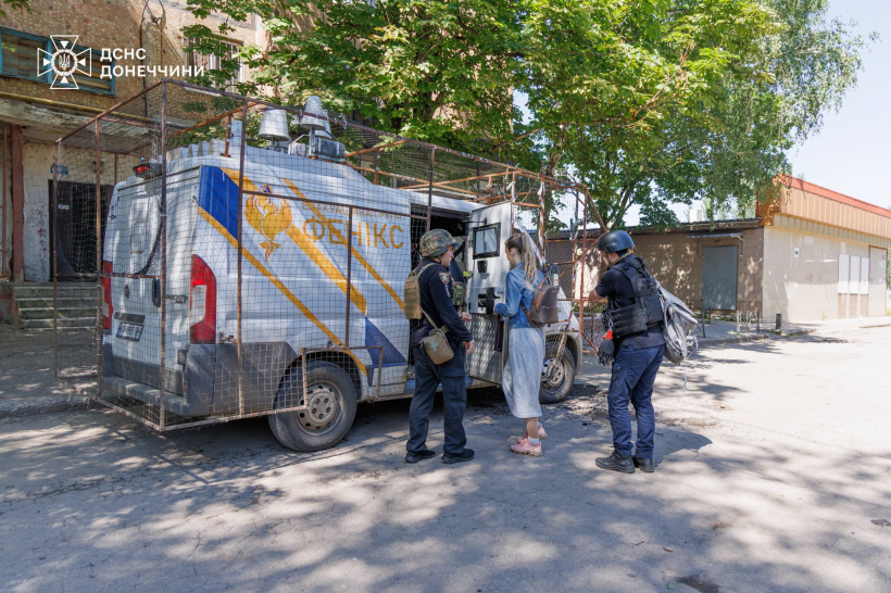 Рятувальники групи "Фенікс" саджають людину в евакуаційний автомобіль