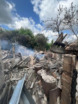 Зруйнована будівля та пожежа на місці ворожого обстрілу.