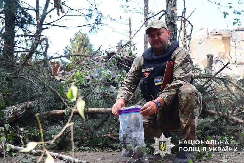 Поліцейський-вибухотехнік тримає в руках пакет з різними уламками або уламками від ворожих снарядів.