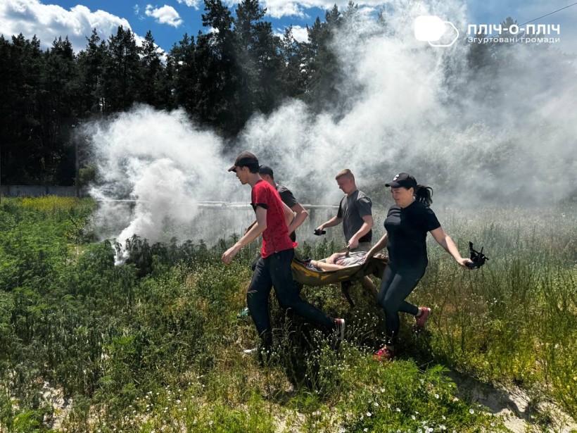 Учасники тренінгу в імпровізованій ситуації, як на полі бою, виносять пораненого "бійця".