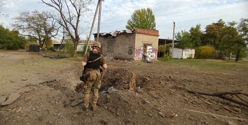 Правоохоронець стоїть біля вирви з-під ворожого обстрілу