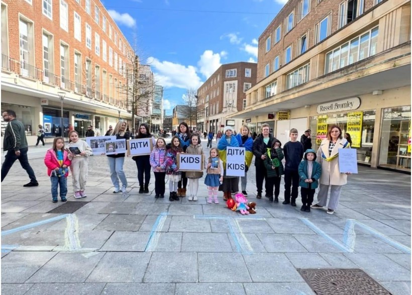 Учасники акції з прапорами України біля напису на асфальті Діти