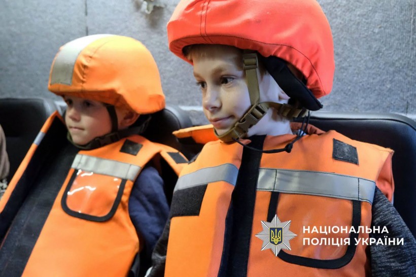 Двоє дітей в машині в бронежилетах та касках