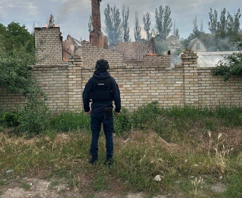 Військовий стоїть біля будівлі, яка зруйнована та палає через ворожий обстріл.