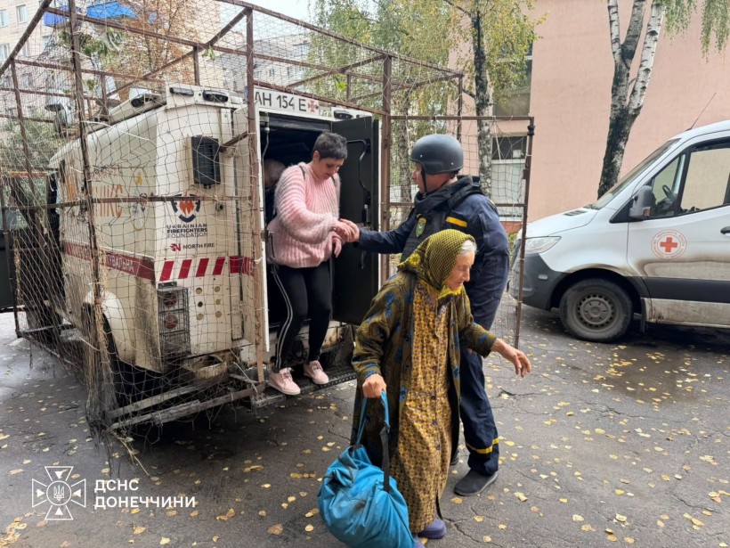 Рятувальник допомагає жінці вийти з евакомобіля