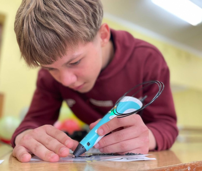 Хлопчик малює 3Д ручкою на аркуші паперу