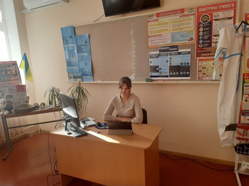 Вчителька, учасниця семінару, сидить в кабінеті за ноутбуком