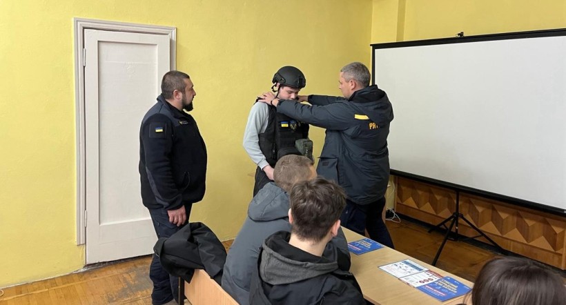 Фахівці ДСНС одягають спеціальне екіпірування на студента коледжу.