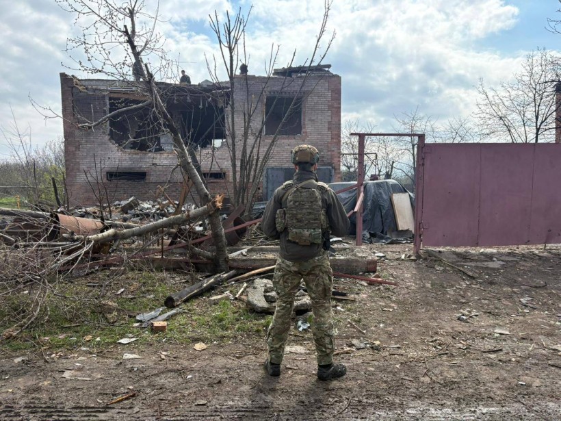 Правоохоронець стоїть біля зруйнованого ворогом будинку